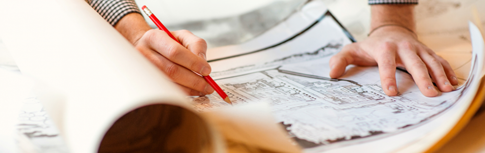 hands holding pencil marking building plans