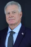Middle aged white man wearing blue suit, shirt and tie