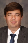 man wearing grey suit, white shirt and blue tie