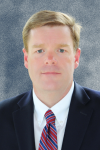 Man wearing black suit, white shirt and red tie