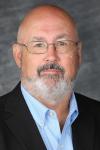 Man with glasses and black jacket over blue shirt