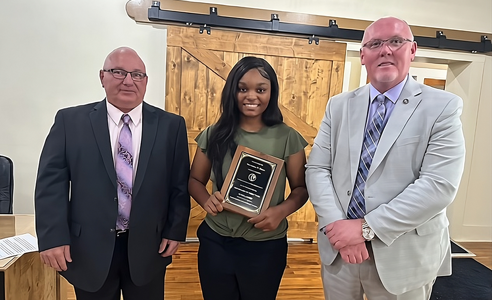 A scholarship winner accepts her award at a county council meeting