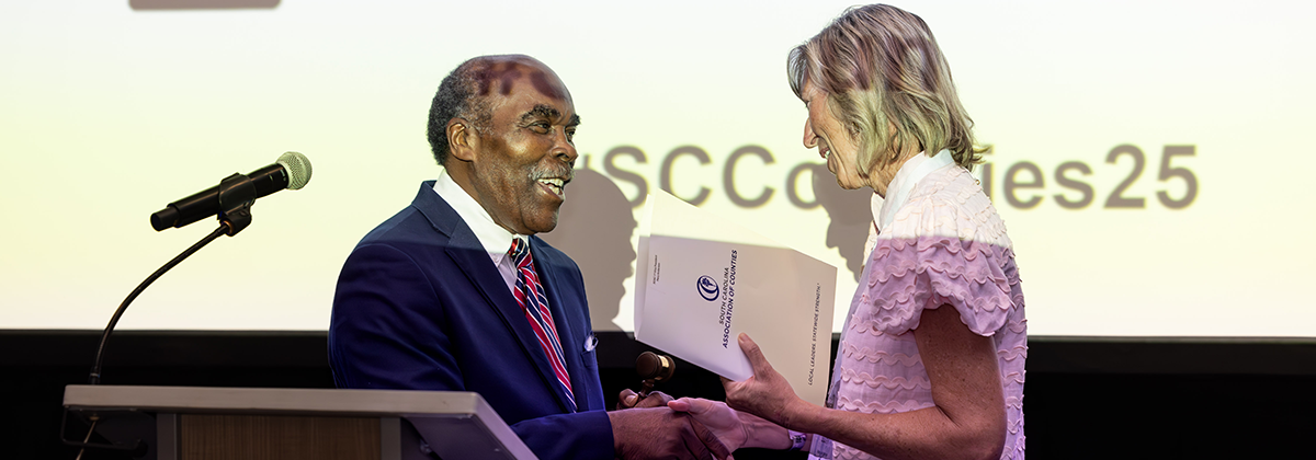 Outgoing SCAC President Bill Robinson passes the gavel to 2025-26 SCAC President Mary Anderson.