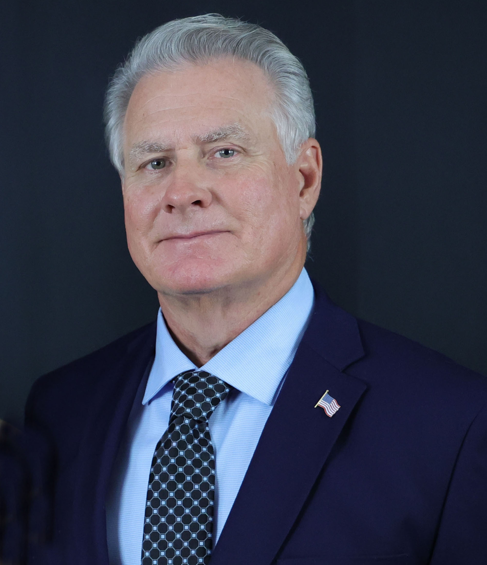 Middle aged white man wearing blue suit, shirt and tie