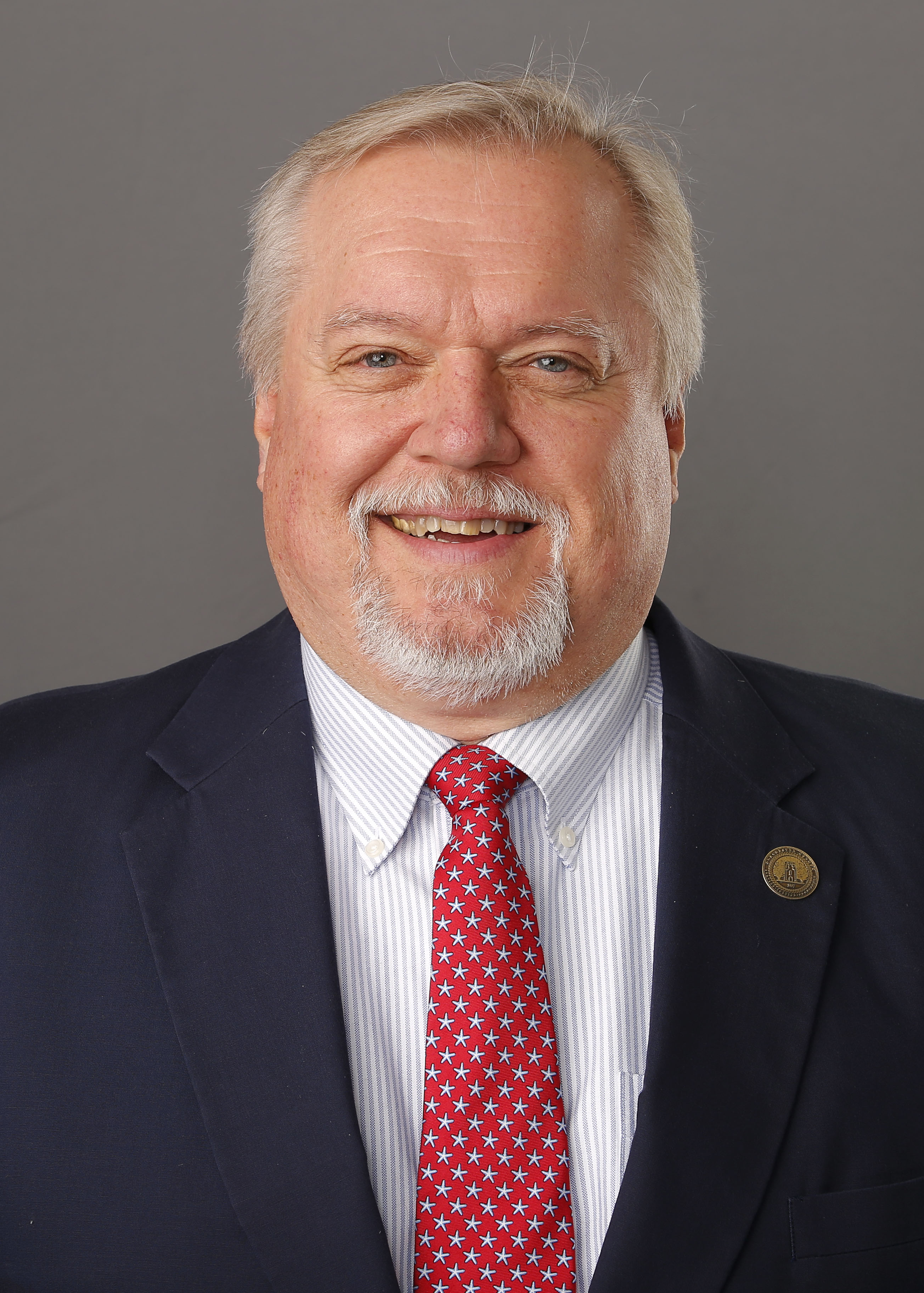 White man with black suit, white shirt and red tie